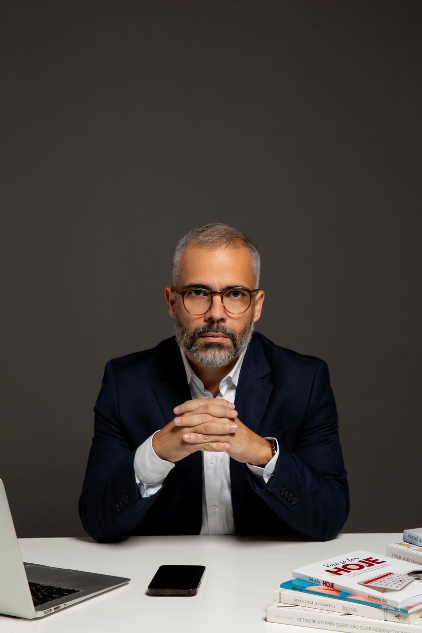Antonio Gil sentado à mesa, mãos entrelaçadas